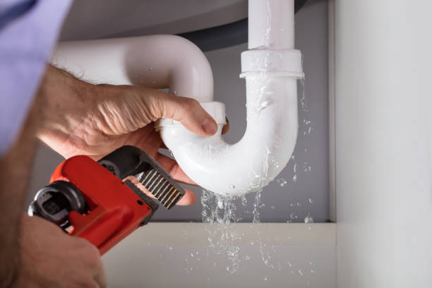 close up of male plumber fixing white sink pipe with adjustable wrench